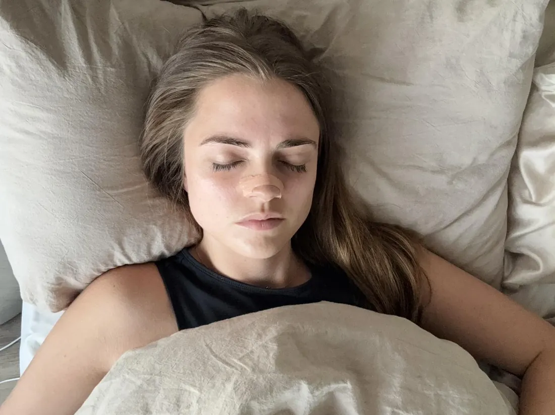 Woman asleep in bed wearing a NasalFlow nasal strip
